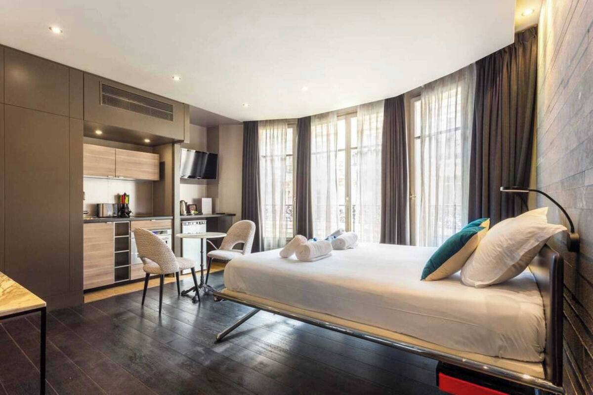 A modern hotel room with a bed, a desk, and a chair.
