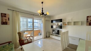Un salon moderne avec balcon, un coin repas et un téléviseur.