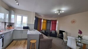 A compact kitchen with a dining area, a sofa, and a small table with chairs. - Fantasy accommodation in Golders Green/ Brent Cross  (London)