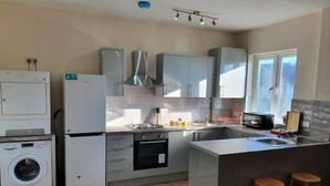 A compact kitchen with a washing machine, a refrigerator, a stove, and a sink. - Fantasy accommodation in Golders Green/ Brent Cross  (London)