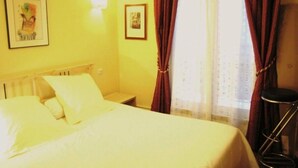 A hotel room with a bed, a nightstand, a chair, and a window with curtains. - Appartement Entre la rue Mouffetard et le Jardin des Plantes (Paris)