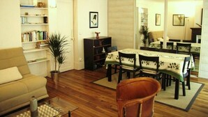 A living room with a sofa, a dining table with chairs, a bookshelf, and a large mirror. - Appartement Entre la rue Mouffetard et le Jardin des Plantes (Paris)