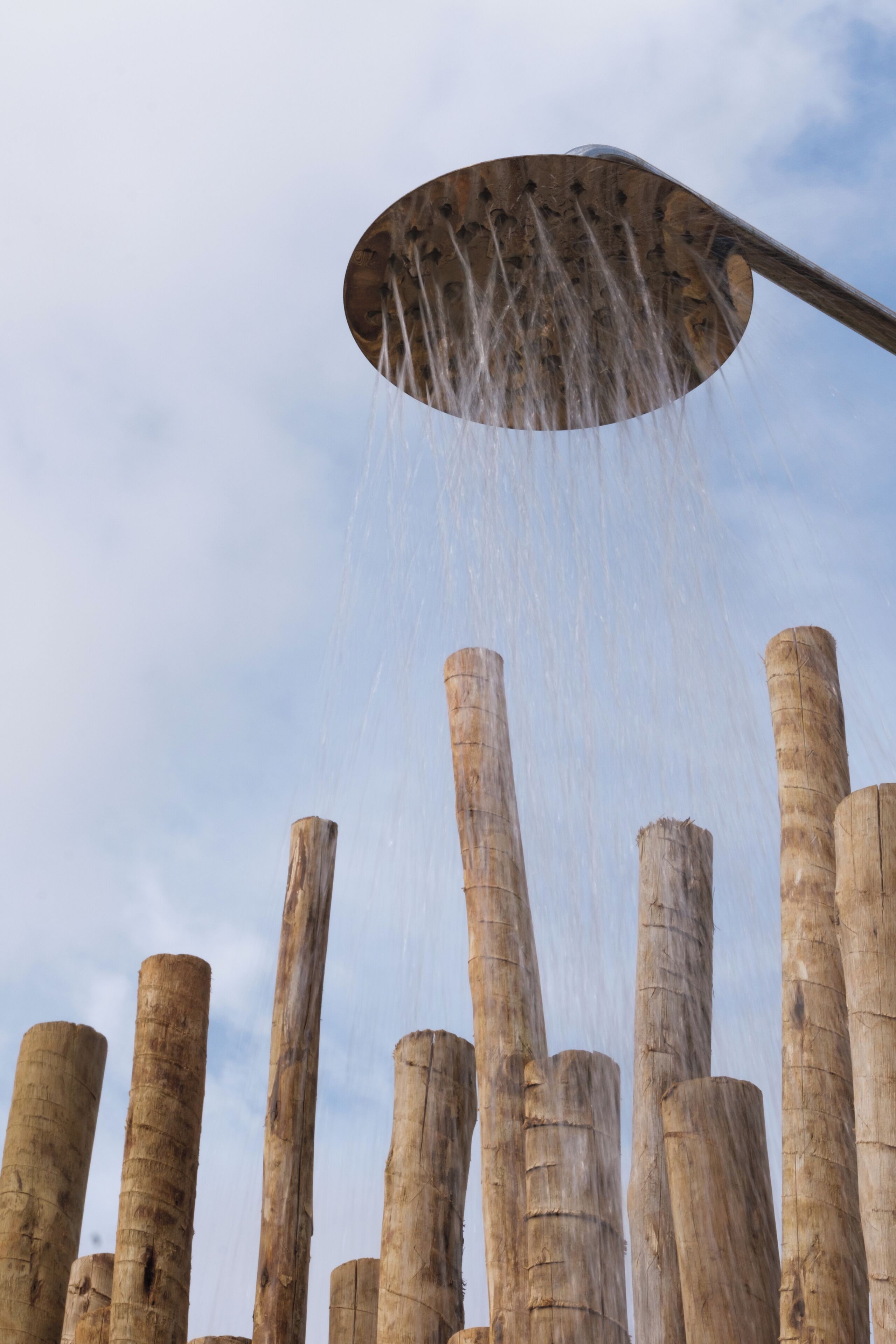 A showerhead with water streaming down wooden pillars.