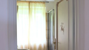 A bathroom with a toilet, shower, and a door with a decorative emblem. - Villa Matilde - Paradiso Costiero, Fronte Mare, Terrazzo e Parcheggio Privato (Badesi)