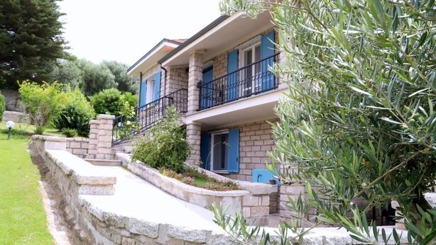A two-story building with a stone facade, blue shutters, and a stone retaining wall. - Villa Matilde - Paradiso Costiero, Fronte Mare, Terrazzo e Parcheggio Privato (Badesi)