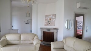 A living room with two beige sofas, a fireplace, and a painting of flowers on the wall. - Villa Matilde - Paradiso Costiero, Fronte Mare, Terrazzo e Parcheggio Privato (Badesi)
