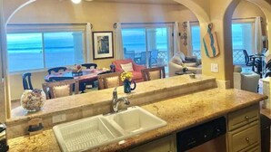 A kitchen with a large island, a double sink, and a view of the ocean through the windows. - Luxurious oceanfront apartment LMB2 (San José del Cabo)