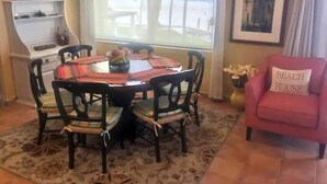 A dining area with a round table, six chairs, and a view of the beach through a large window. - Luxurious oceanfront apartment LMB2 (San José del Cabo)