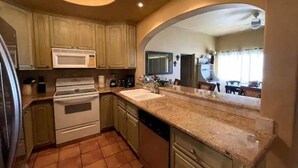 A kitchen with wooden cabinets, a microwave, stove, and a dishwasher. - Luxurious oceanfront apartment LMB2 (San José del Cabo)