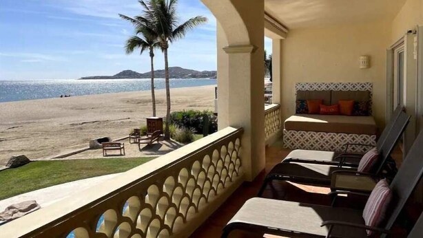 A balcony with a view of the beach, a sofa, and a few chairs. - Luxurious oceanfront apartment LMB2 (San José del Cabo)