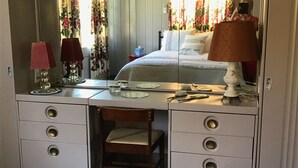Une chambre à coucher comprenant un lit, une commode avec des tiroirs, une chaise, un miroir et une lampe.