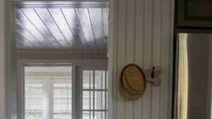 Eine Küche mit einem Edelstahlkühlschrank, einer Obstschale auf der Arbeitsfläche und einem hölzernen Hut an der Wand.