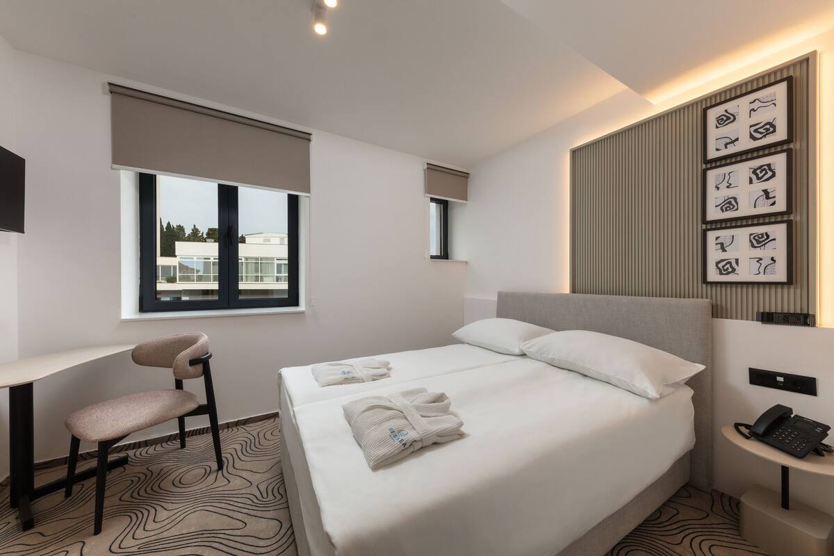 A modern hotel room with a bed, a desk, and a chair.