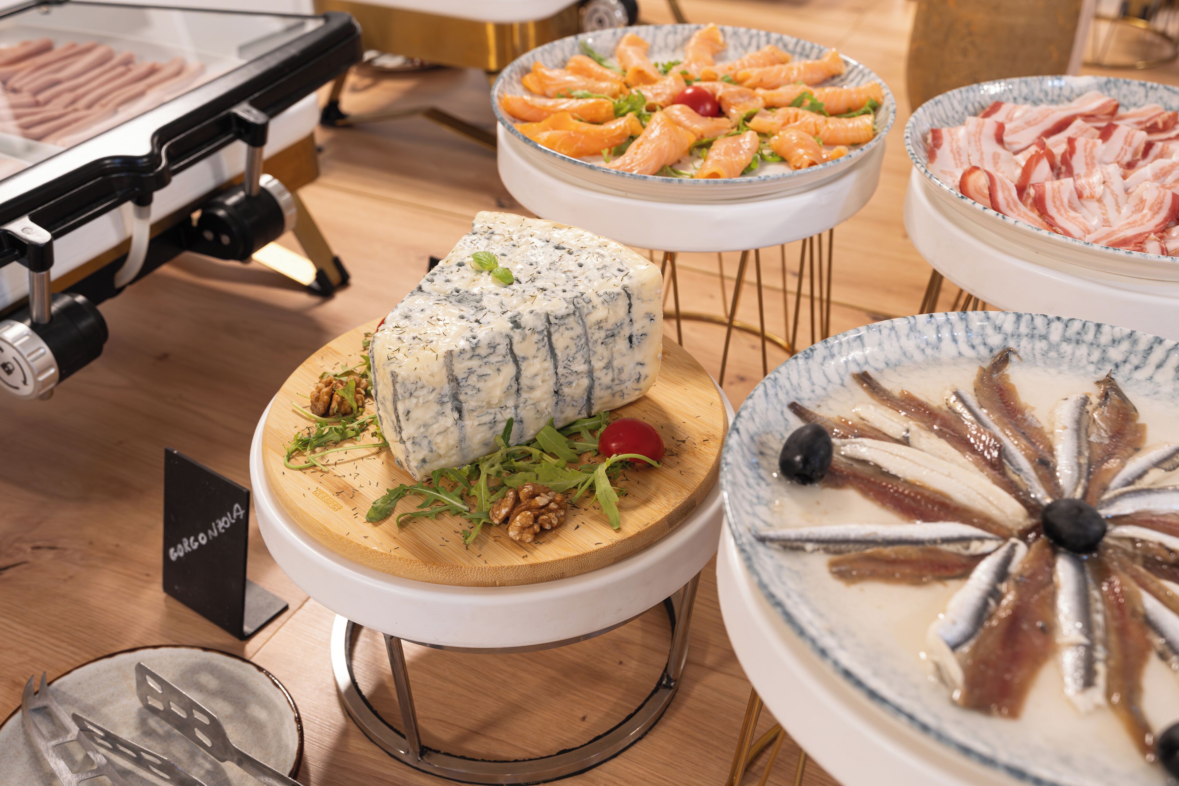 A buffet with various food items including cheese, salmon, and other dishes.