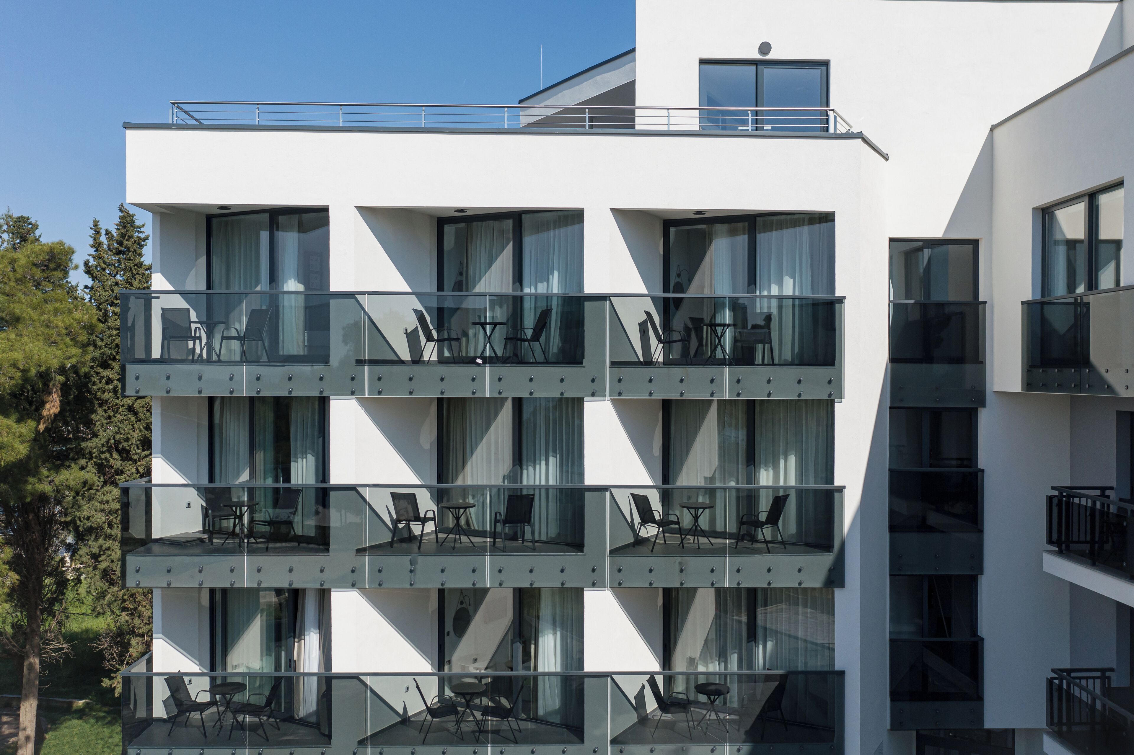 Un edificio moderno de varios pisos con balcones, ventanas amplias y zonas de estar al aire libre.