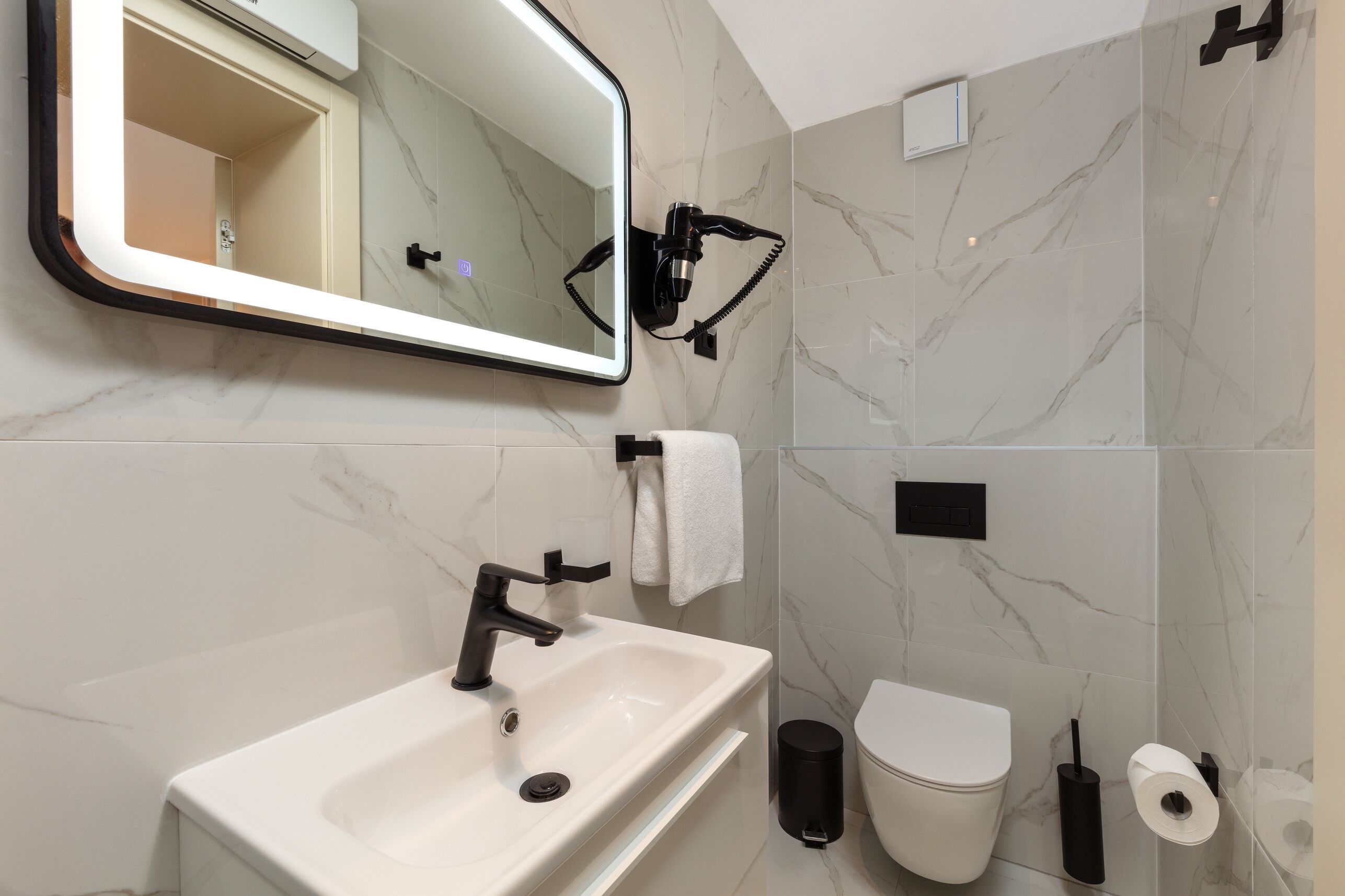 A modern bathroom with a large mirror, a sink, a toilet, and a shower area.