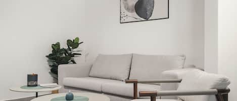 A modern living room with a grey sofa, a round coffee table, and a small side table with a lamp.
