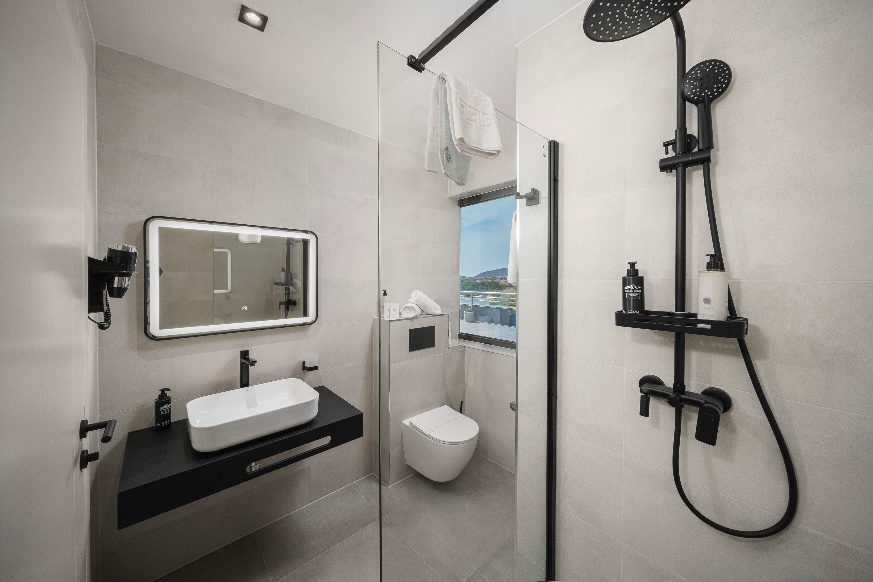 A modern bathroom with a glass-enclosed shower, a white sink, and a toilet.