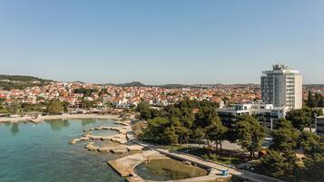 A coastal cityscape with a prominent modern building, clear waters, and a park area.