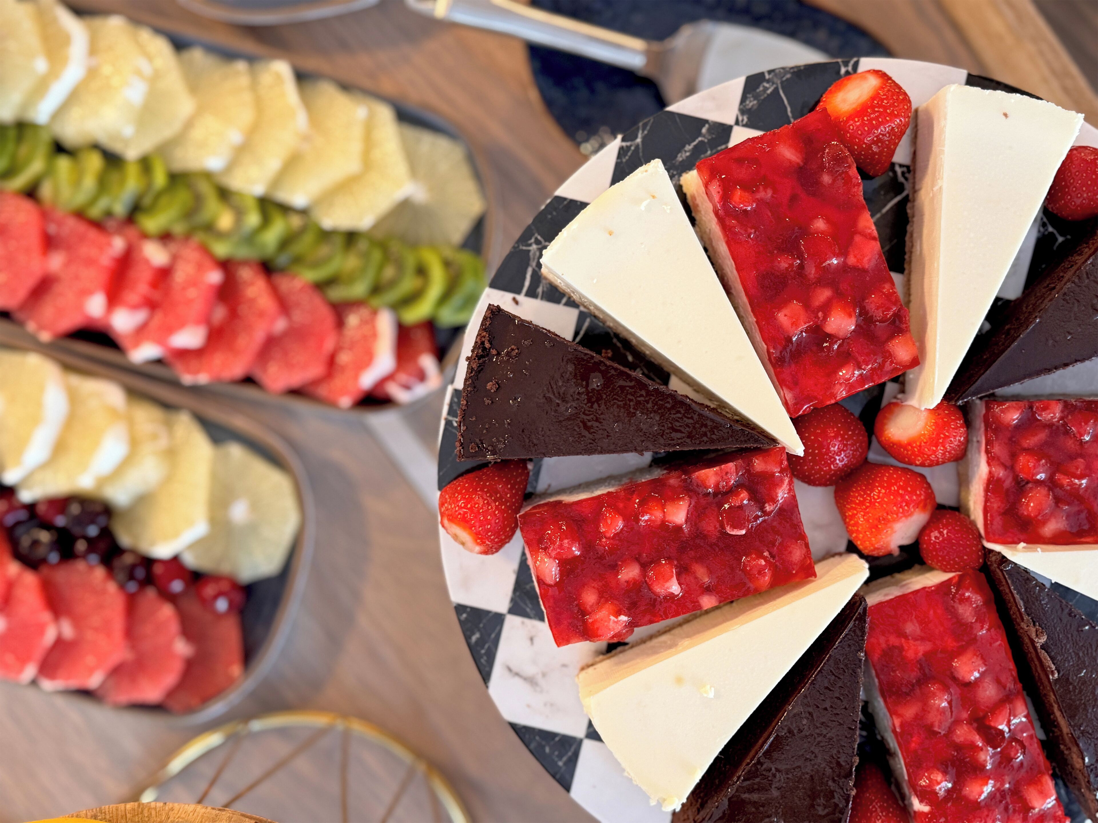 Une variété de desserts, notamment des tartes au chocolat et aux fraises, disposés sur une assiette à carreaux.