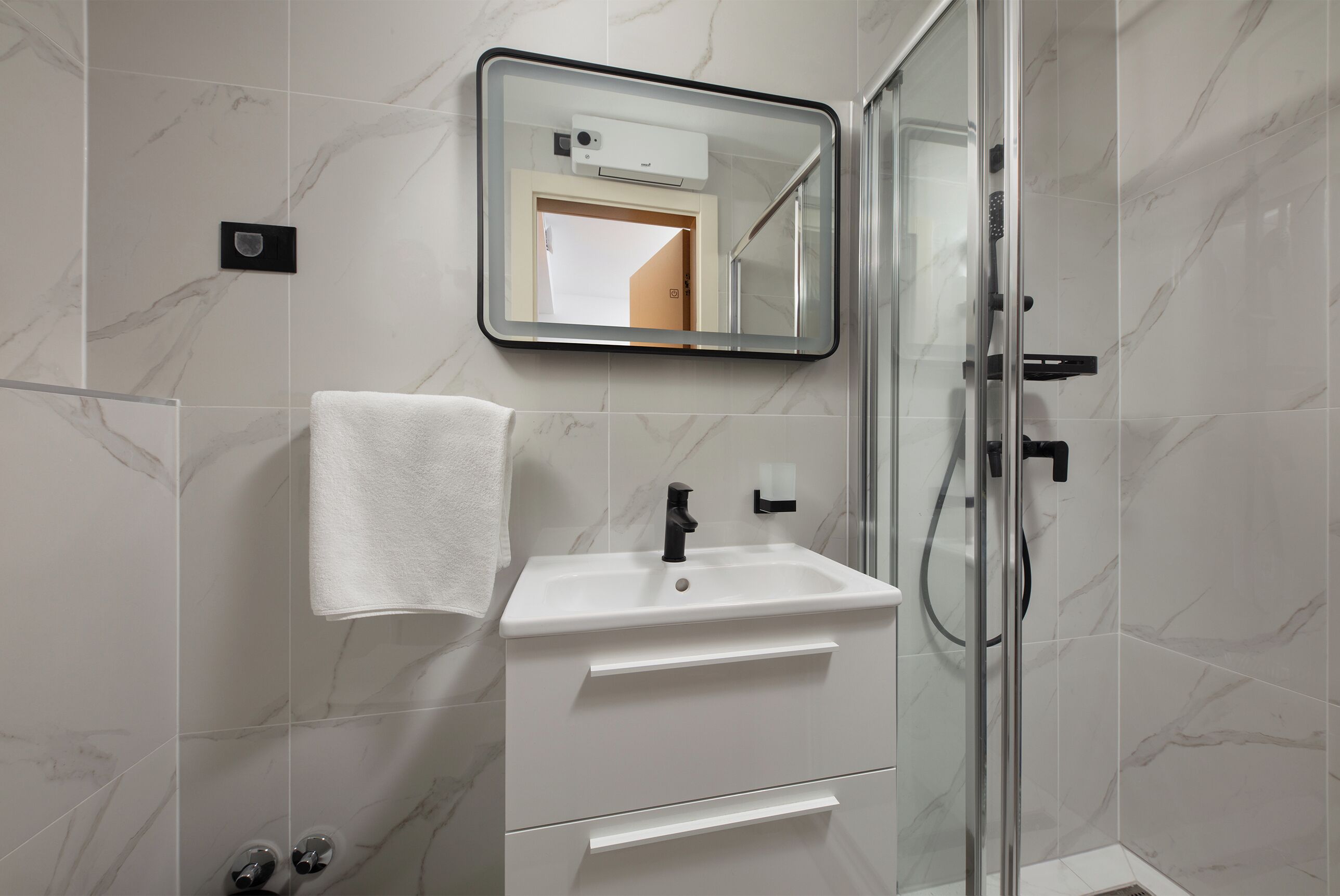 A bathroom with a white sink, a mirror, and a glass shower enclosure.