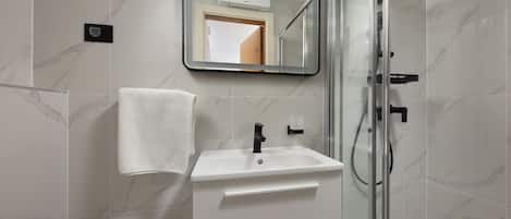 A bathroom with a white sink, a mirror, and a glass shower enclosure.