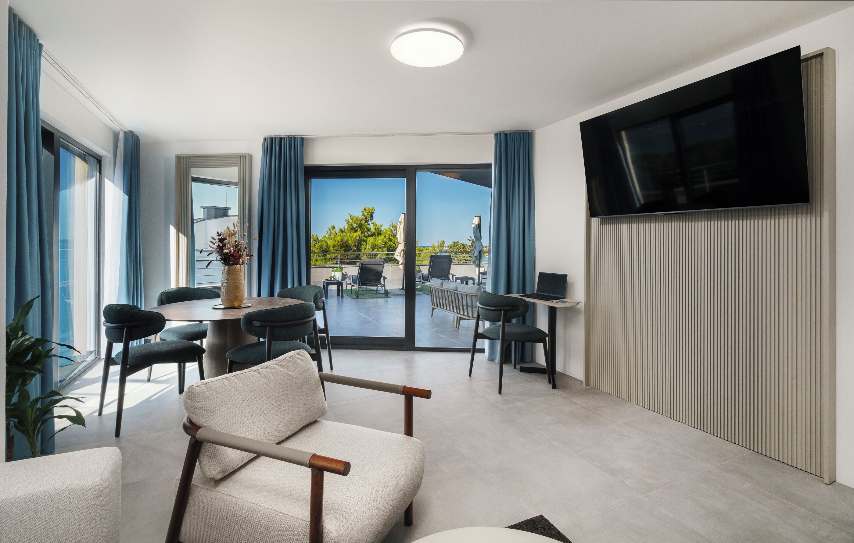 Ein modernes Hotelzimmer mit Essbereich, einem Flachbildfernseher und einem Balkon mit Blick.
