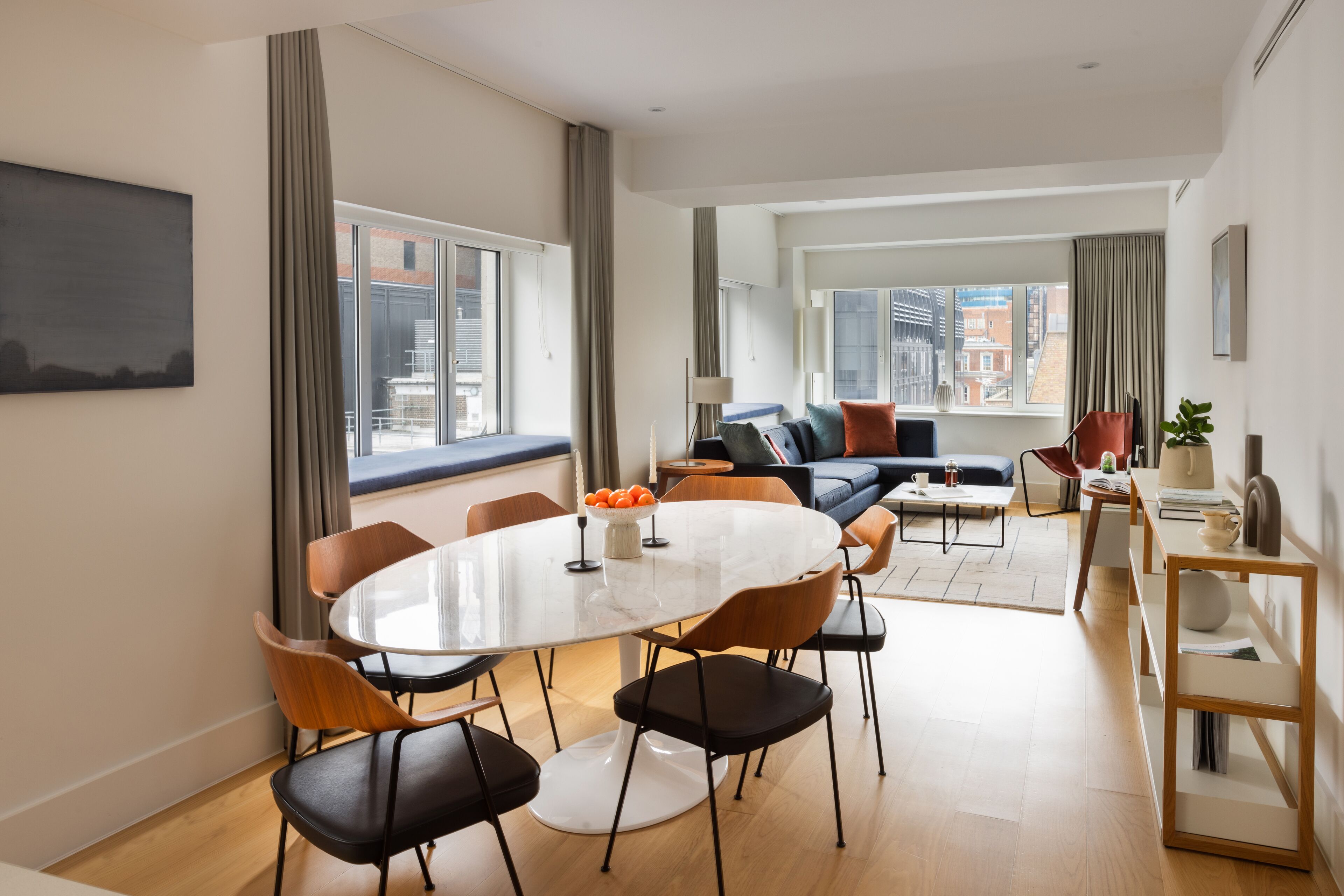 Ein modernes Wohnzimmer mit Essbereich, großen Fenstern und Blick auf die Stadt.