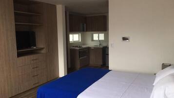 Una habitación de hotel con cama, armario y kitchenette.