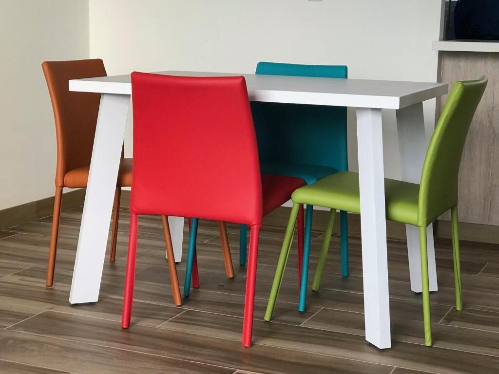 Une table à manger avec quatre chaises, chacune d’une couleur différente.