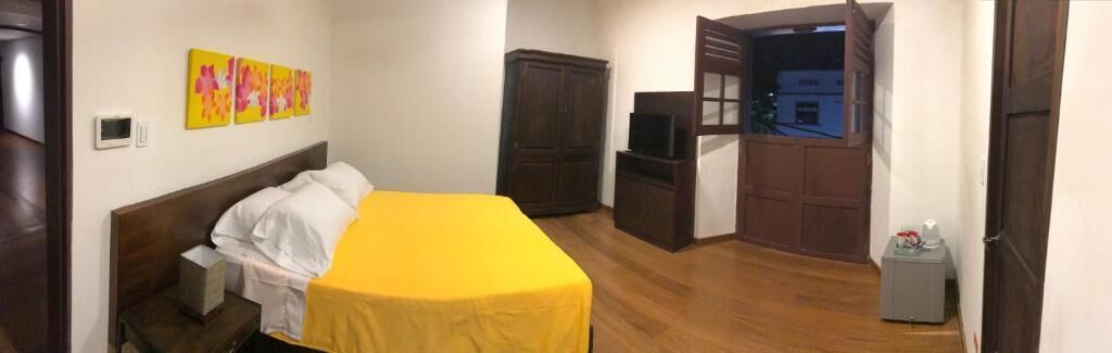 Una habitación con cama, televisión, armario y una pequeña mesa.