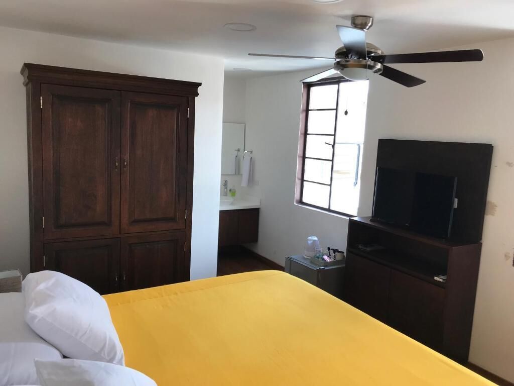 A bedroom with a bed, a ceiling fan, a TV, and a wardrobe.