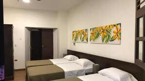 Habitación de hotel con tres camas individuales, un ventilador de techo y dos obras de arte con motivos florales.