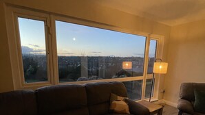 A living room with a large window, a sofa, a chair, and a lamp.