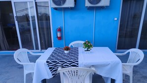 A table with a patterned tablecloth, white chairs, and a potted plant. - Bob Apartments (Calodyne)