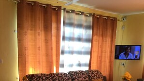 A living room with a sofa set, a coffee table, and a TV mounted on the wall. - Bob Apartments (Calodyne)