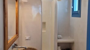 A bathroom with a wooden-framed mirror, a sink, and a shower area. - Tilos Villa - Apartment Comfort (Tilos)