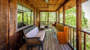 A covered porch with wooden railings, a bench, and a table.