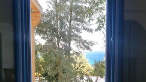 Une fenêtre donnant sur un arbre et un bâtiment. On peut voir trois objets cylindriques sur le rebord de la fenêtre.