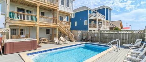 Een zwembadgedeelte met een jacuzzi, ligbedden en een houten terras.