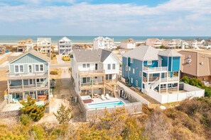 A coastal residential area with multiple two-story houses, a swimming pool, and a beach in the background.