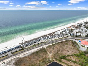 A coastal hotel with a beach view, multiple-story buildings, and a parking area.