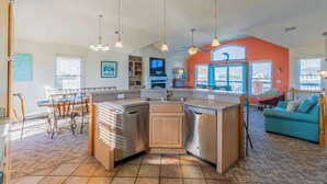Una cucina moderna con isola centrale, elettrodomestici in acciaio inossidabile e illuminazione a sospensione.