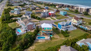 Una zona residenziale costiera con case, una piscina e una spiaggia sullo sfondo.