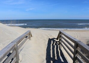 A wooden boardwalk leading to a sandy beach with ocean views.