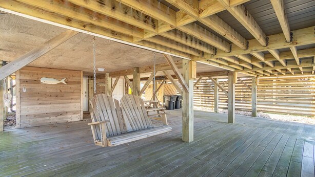 Un patio in legno con un'altalena, pareti in legno e una decorazione a forma di pesce appeso.