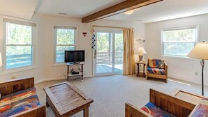 A living room with a television, a sofa, a coffee table, a lamp, and a chair. - Oceanside Home Just a Short Walk or Bike Ride to the Beach, Shops, and Dining! (Corolla)