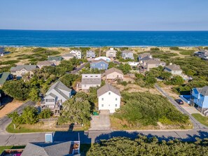 An aerial view of a coastal residential area with houses, a beach, and a clear sky.