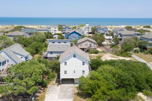 A coastal residential area with multiple houses, a clear view of the ocean, and a sandy beach in the background.