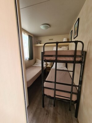 A bunk bed room with a window, a bedside table, and a ceiling light.